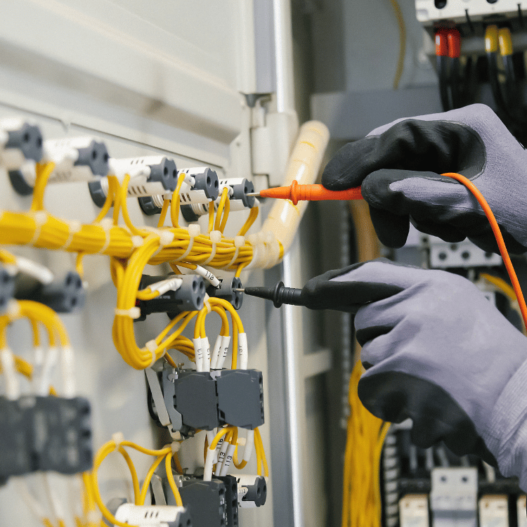 Kädet jotka mittaa yleismittarilla sähkötaulua